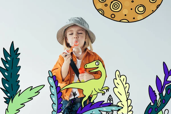 Niedliches Kind mit Hut und orangefarbenem Hemd weht Seifenblasen mit Dinosaurier zu Fuß zwischen Pflanzen Märchen Illustration isoliert auf grau — Stockfoto