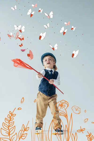 Carino e biondo capretto in gilet retrò e cappello cattura farfalle con rete farfalla sul prato fatato con fiori — Foto stock