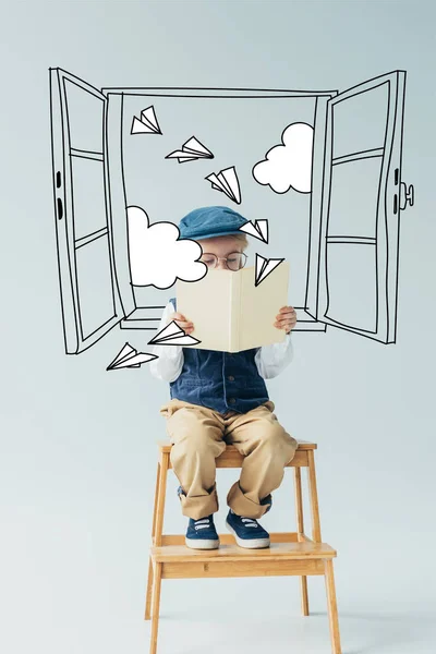 Lindo niño sentado en escaleras de madera y libro de lectura sobre fondo gris con ventana de hadas, planos de papel y nubes ilustración - foto de stock