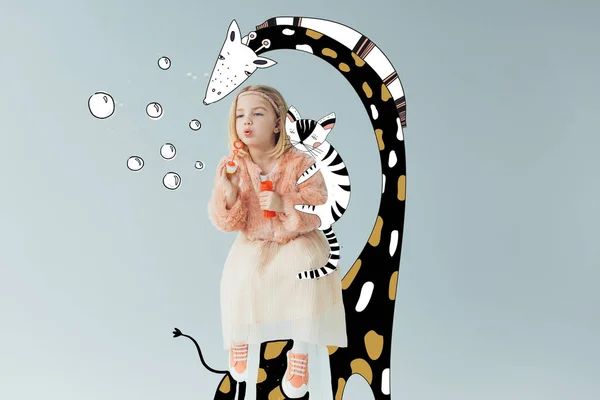 Adorable kid in faux fur coat and skirt sitting on fairy giraffe and blowing soap bubbles isolated on grey — Stock Photo