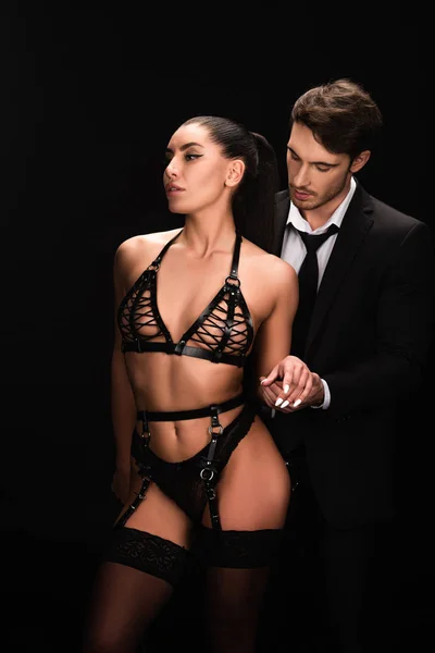 Man in formal wear with bdsm girl isolated on black — Stock Photo