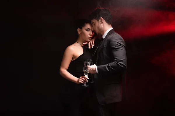 Hermosa pareja elegante con copas de champán en negro - foto de stock