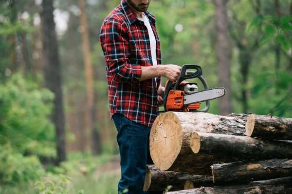 Vista cortada de madeira lenhador corte redondo com motosserra na floresta — Fotografia de Stock