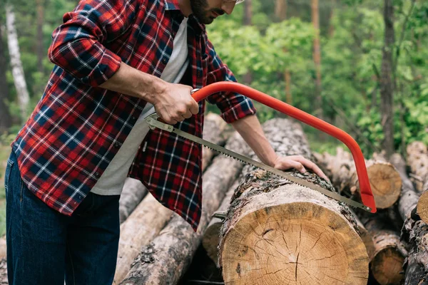 Partial view of lumberer cutting log with handsaw in forest — Stock Photo