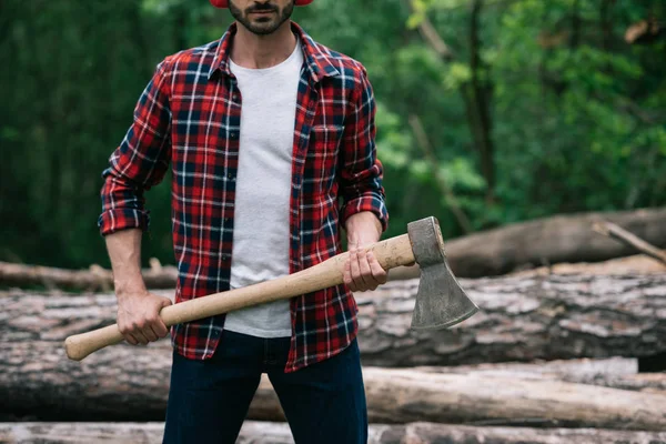 Vue recadrée du bûcheron en chemise à carreaux tenant la hache en forêt — Photo de stock