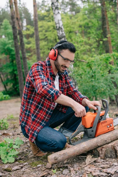 Holzfäller in lärmintensiven Kopfhörern stellt Kettensäge im Wald ein — Stockfoto