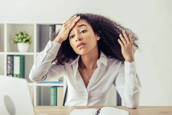 Pretty african american businesswoman holding hand on head while suffering from heat in office — Stock Photo