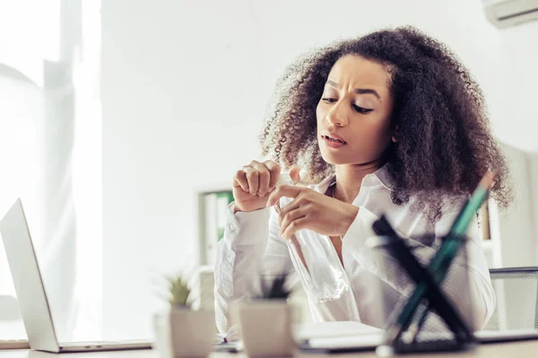 Selective focus of african american businesswoman holding plastic bottle with water while suffering from summer heat in office — Stock Photo