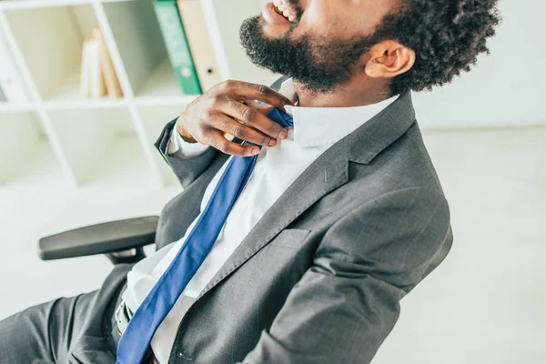 Частковий погляд афроамериканців бізнесмен зворушливий краватку, страждає від спеки в офісі — стокове фото