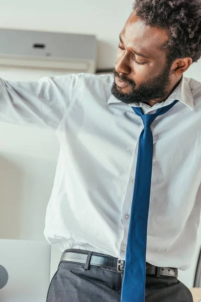 Épuisé homme d'affaires afro-américain souffrant de chaleur estivale et regardant chemise moite — Photo de stock