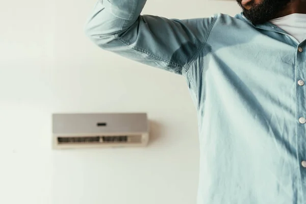 Vista parcial del hombre afroamericano en camisa sudorosa que sufre de calor de verano - foto de stock