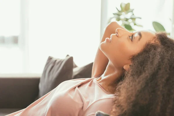 Красива афроамериканка лежить на дивані, страждаючи від літньої спеки вдома — стокове фото