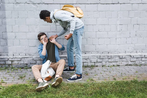 Arrabbiato e bruna africano americano ragazzo bulling spaventato ragazzo in occhiali — Foto stock