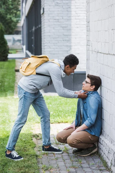 Aggressive and brunette african american boy bulling scared boy in glasses — Stock Photo