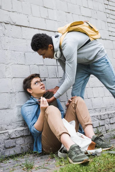 Agresivo africano americano chico bulling asustado chico en gafas - foto de stock