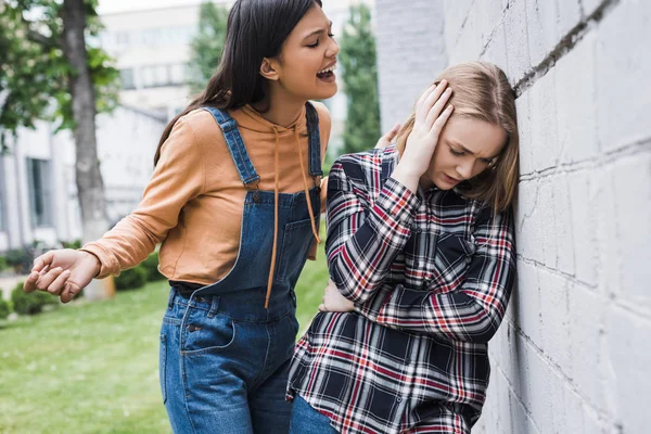 Aggressive and brunette teenager screaming at blonde and scared teenager — Stock Photo