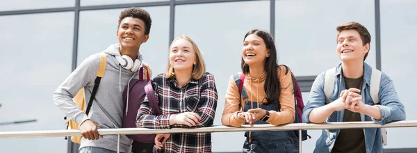 Panoramic shot of happy teenagers smiling and looking away — Stock Photo