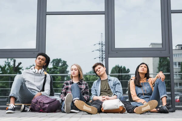 Attraktive und verträumte Freunde, die draußen sitzen und wegschauen — Stockfoto