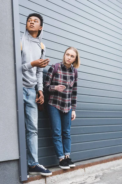 African american boy and blonde teenager looking away, smoking cigarettes and holding beer — Stock Photo
