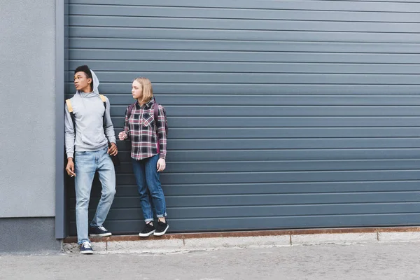 African american boy and blonde teenager looking away, smoking cigarettes and holding beer — Stock Photo