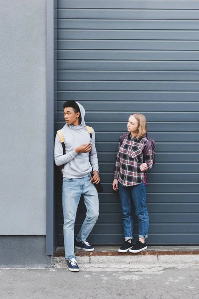 Afroamericano chico y rubia adolescente mirando hacia otro lado, fumando cigarrillos y sosteniendo cerveza - foto de stock