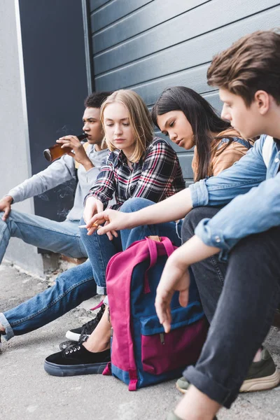 Brünette und blonde Teenager sitzen, trinken Bier und rauchen Zigarette — Stockfoto