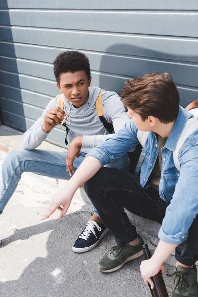 Friends sitting, talking, holding beer and smoking cigarettes outside — Stock Photo