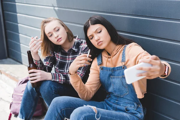 Selective focus of friends smoking cigarettes, holding beer and taking selfie — Stock Photo