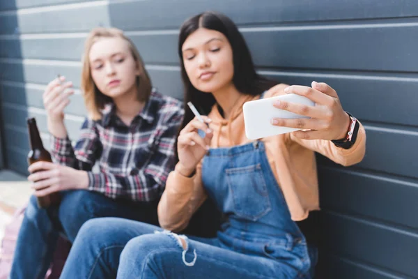 Foyer sélectif des amis fumant des cigarettes, tenant de la bière et prenant selfie — Photo de stock