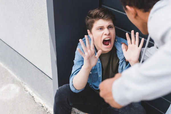 Enfoque selectivo de afroamericano chico puñetazo asustado y gritando chico - foto de stock