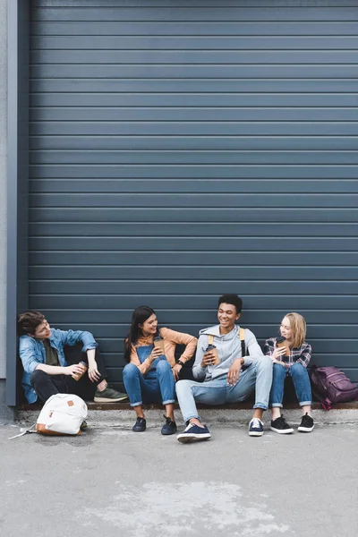 Teenager sitzen, trinken Kaffee aus Einwegbechern und lächeln — Stockfoto