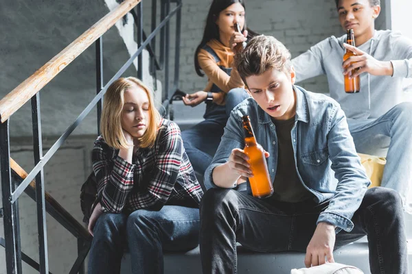 Adolescenti seduti sulle scale, bere birra da bottiglie di vetro e parlare — Foto stock