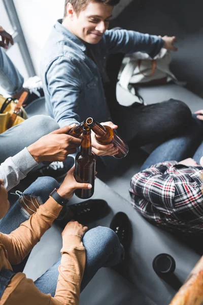 Cropped view of smiling teenagers sitting on stairs and clinking — Stock Photo