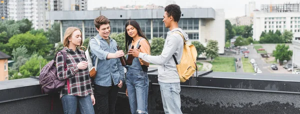 Plano panorámico de adolescentes sonrientes tintineo y fumar cigarrillo - foto de stock