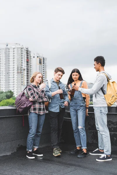 Adolescentes felizes batendo, falando e fumando cigarro no telhado — Fotografia de Stock