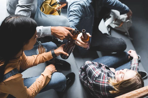 Teilansicht von Teenagern, die auf Treppen sitzen, lächeln und klirren — Stockfoto