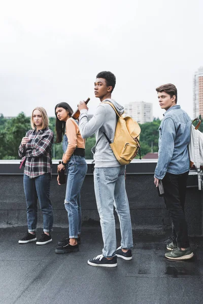 Teenagers holding beer, smoking cigarette and looking away on roof — Stock Photo