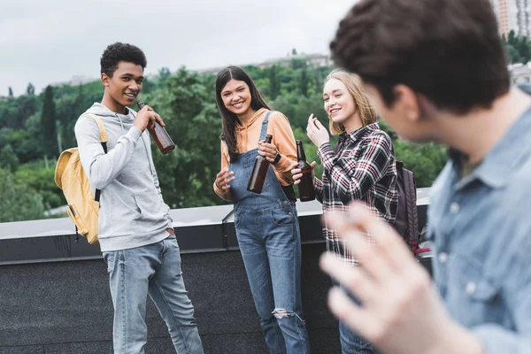 Enfoque selectivo de adolescentes felices sosteniendo cerveza y sonriendo - foto de stock