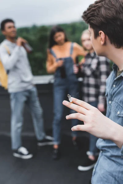 Вибірковий фокус підлітка палити сигарету з друзями на даху — стокове фото
