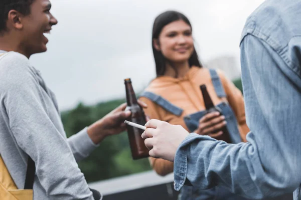 Focus selettivo di adolescenti che tengono bottiglie di vetro con birra e fumo di sigaretta — Foto stock