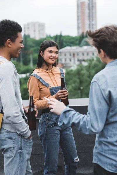 Smiling teenagers holding glass bottles with beer and smoking cigarette — Stock Photo