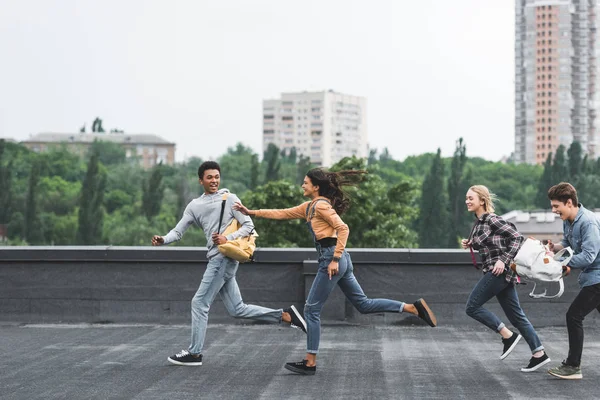 Playful and happy teenagers running on roof and smiling — Stock Photo