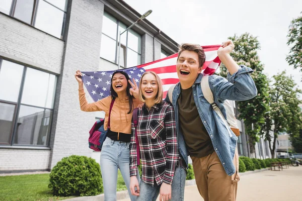 Adolescentes felizes sorrindo, segurando a bandeira americana e olhando para a câmera — Fotografia de Stock