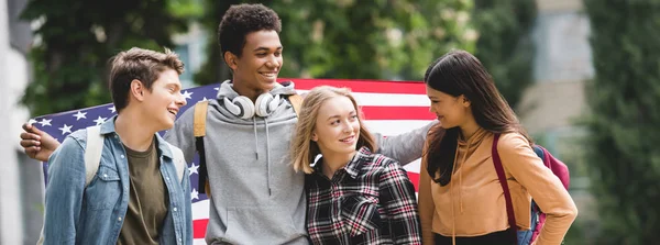 Tiro panorâmico de adolescentes segurando bandeira americana e falando — Fotografia de Stock