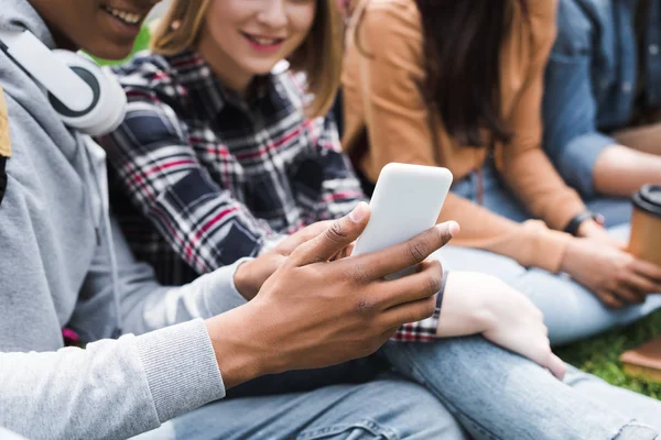 Cropped view of smiling and happy teenagers looking at smartphone — Stock Photo