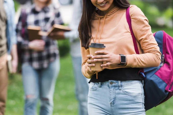 Cropped view of smiling teenager holding paper cup with coffee — Stock Photo