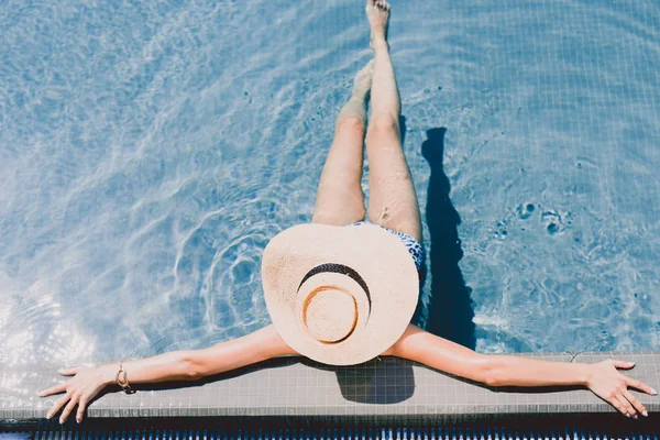 Vue aérienne de la jeune femme en chapeau de paille relaxant dans la piscine — Photo de stock