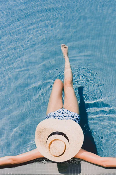 Vue aérienne de la jeune femme en chapeau de paille reposant dans la piscine — Photo de stock