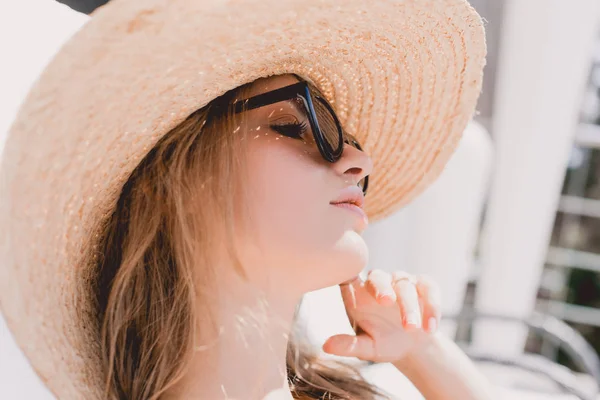 Retrato de atractiva mujer rubia de ensueño tomando el sol en gafas de sol y sombrero de paja - foto de stock