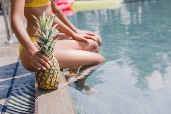 Foco seletivo de menina amigo sentado com abacaxi perto da piscina — Fotografia de Stock